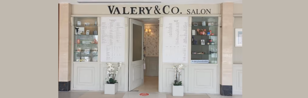 The storefront of VALERY & CO. SALON with menus and display cases flanking the entrance.