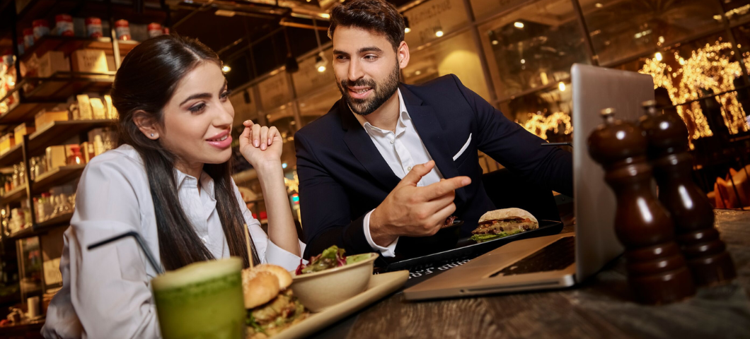 Two professionals enjoying a meal and coffee while having a business meeting in a modern restaurant at Bay Square, Business Bay, Dubai.