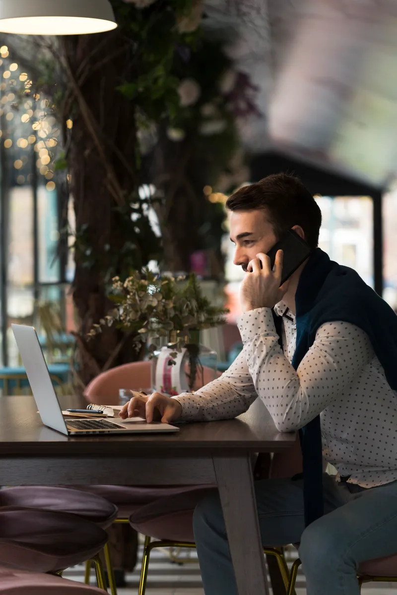 auto-entrepreneur qui parle au téléphone avec un client devant son oridnateur
