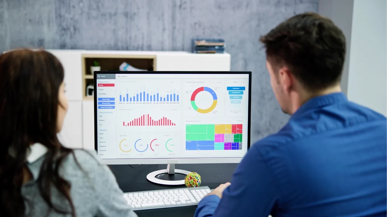 Deux personnes analysent des graphiques et des données sur un écran d’ordinateur