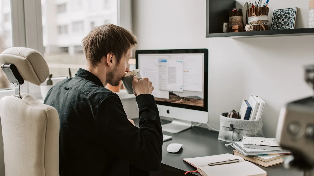 Homme assis à un bureau, travaillant sur un ordinateur avec des documents à proximité