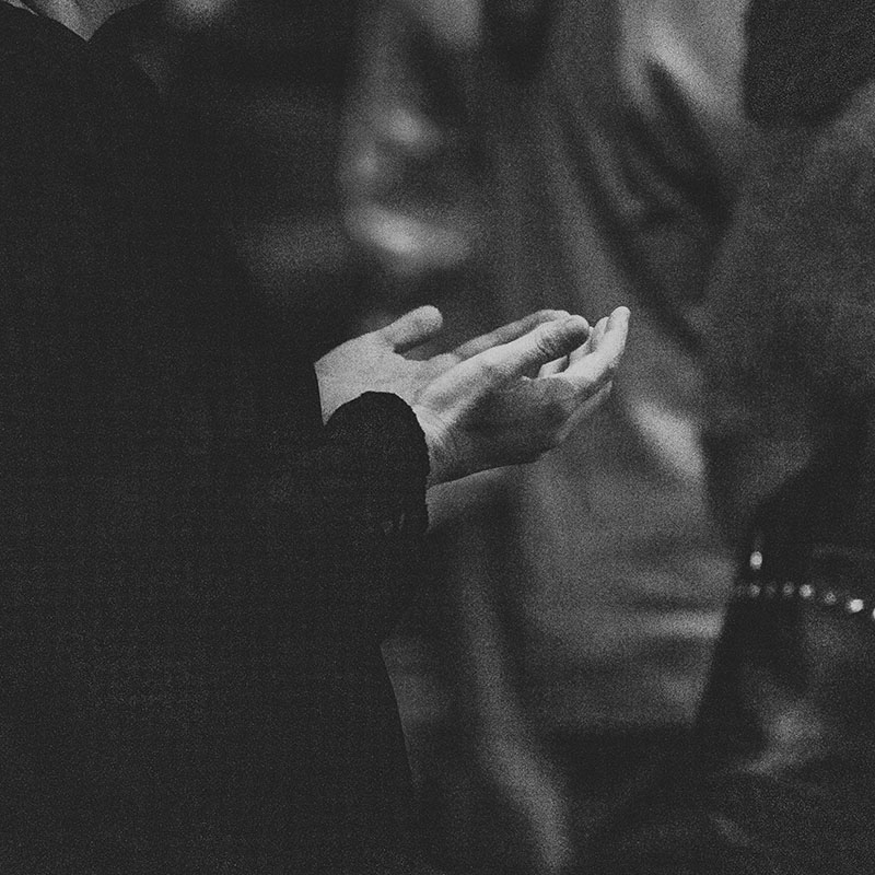 Black and white photo of a person's hands held open and raised, suggesting a gesture of prayer or pleading.