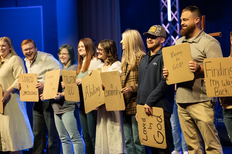 A woman fills up a cup of coffee from a carafe.