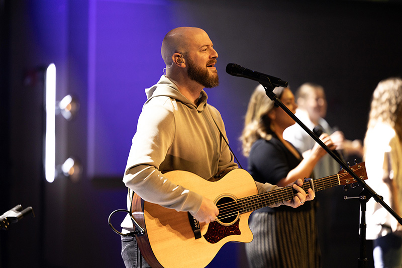 A woman fills up a cup of coffee from a carafe.
