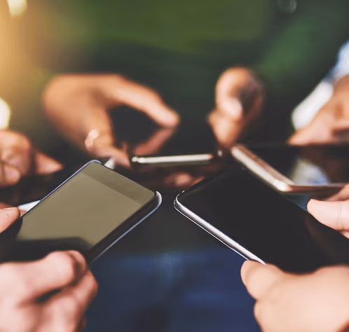 Close-up of several hands holding smartphones with blank screens.