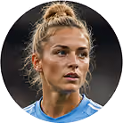 Close-up of a female soccer player with blonde hair in a bun wearing a blue jersey.