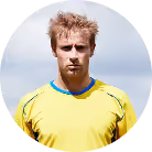 Man with short blond hair and beard in yellow sports jersey against a blue sky.