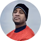 Man wearing a black beanie and red shirt with a blue collar looking at the camera.