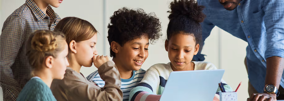 A group of children and an adult gathered around a laptop, engaged in a learning activity.