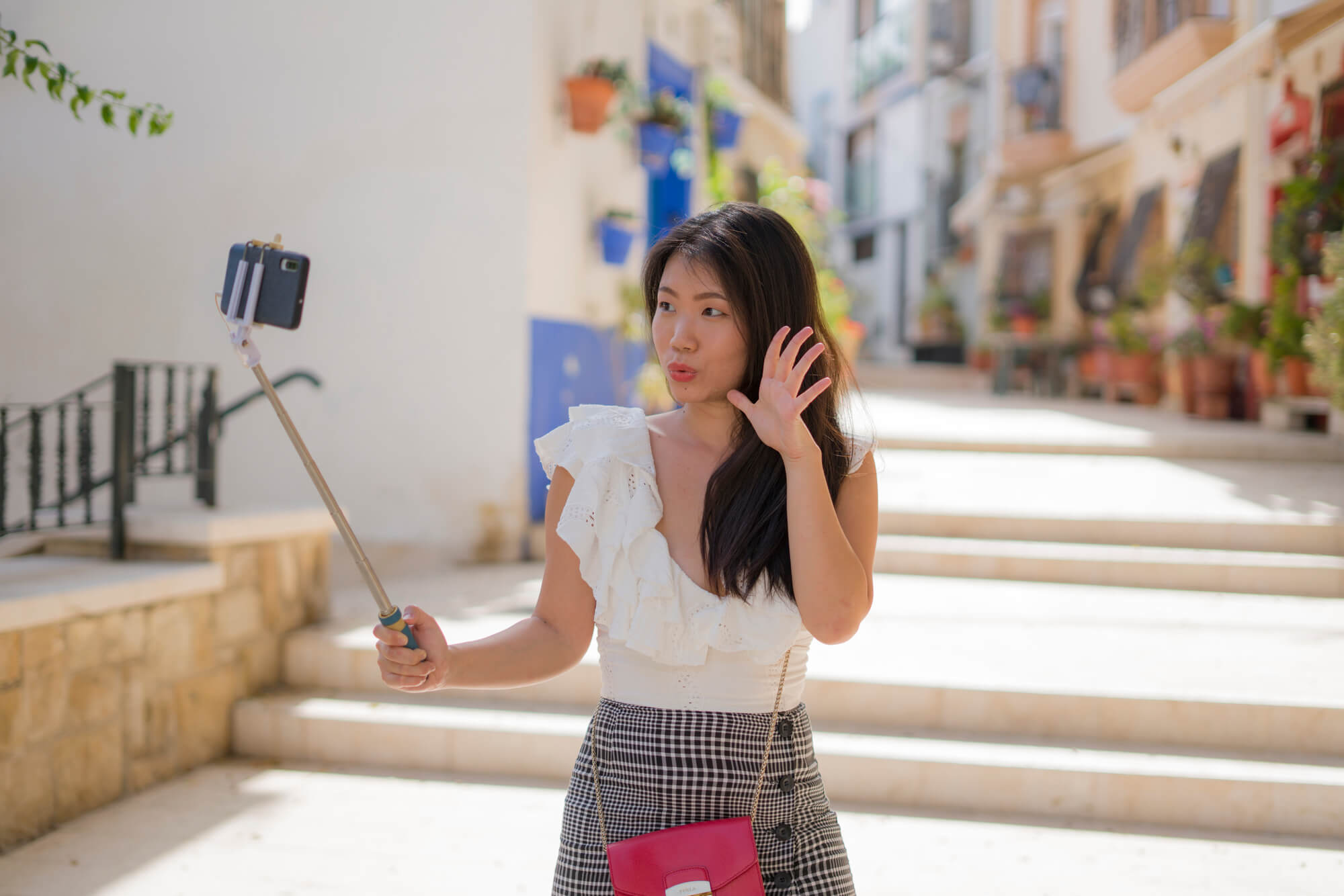 girl vlogging in the street using a phone held by a monopod