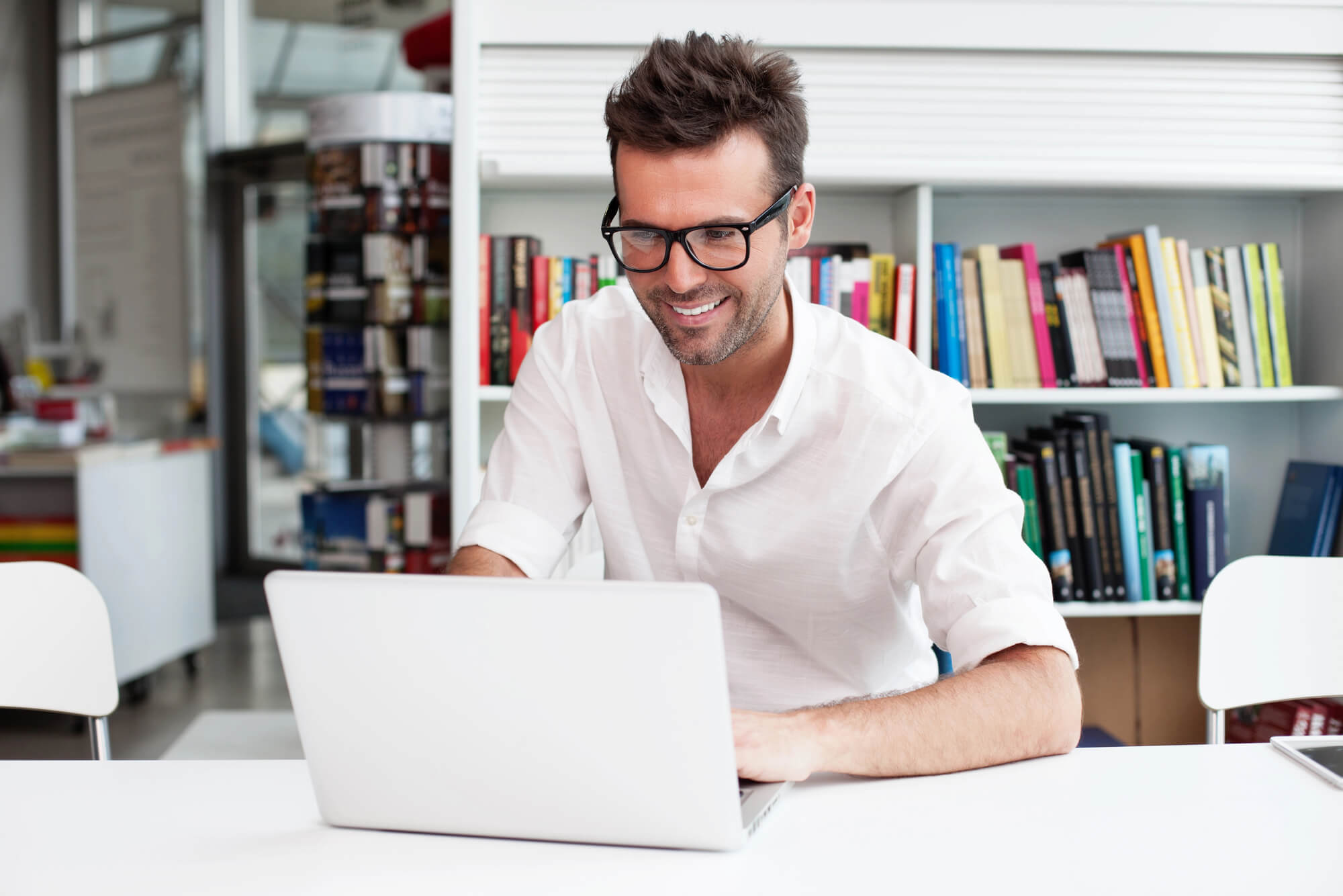 male professional smiling as he looks at his laptop