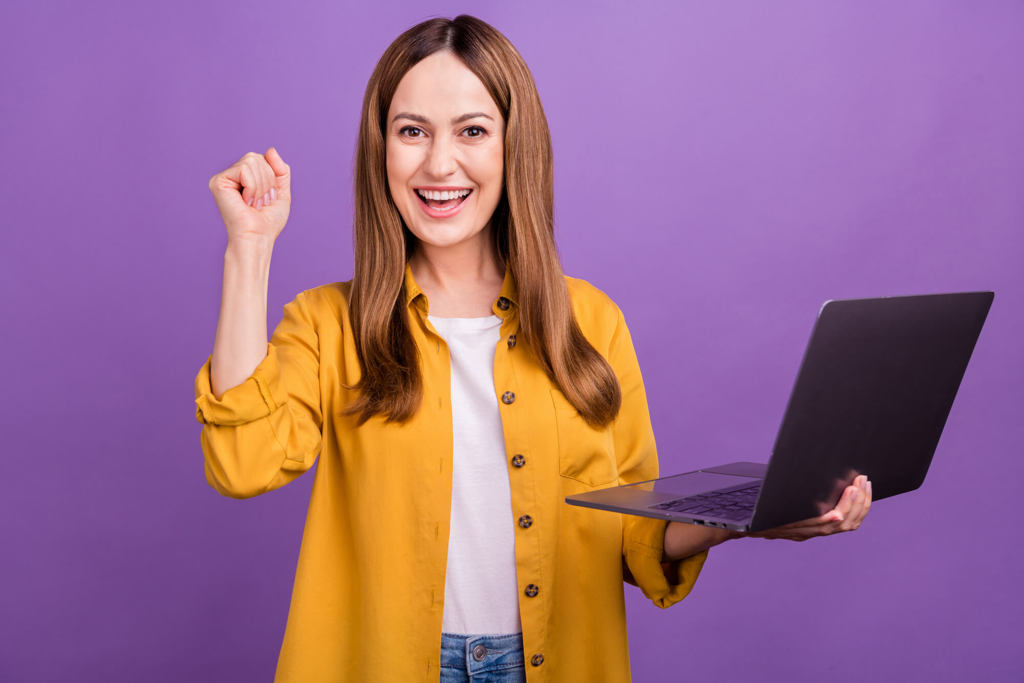 young female professional holding laptop while rejoicing 