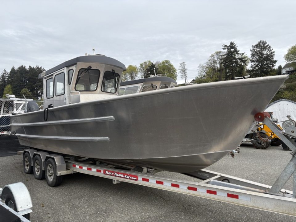 Ortun aluminum cabin cruiser boat on a trailer at a marina.