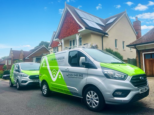 Big Green Electrical vans outside a home with rooftop solar panels