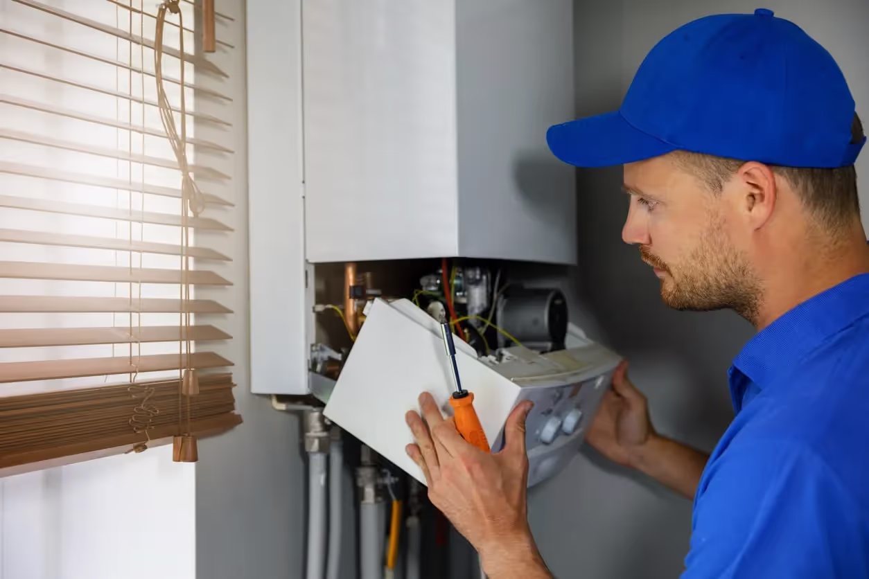 A technician in blue dress repairing a furnace