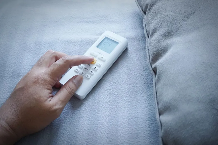 A close shot of person using a remote control of an AC