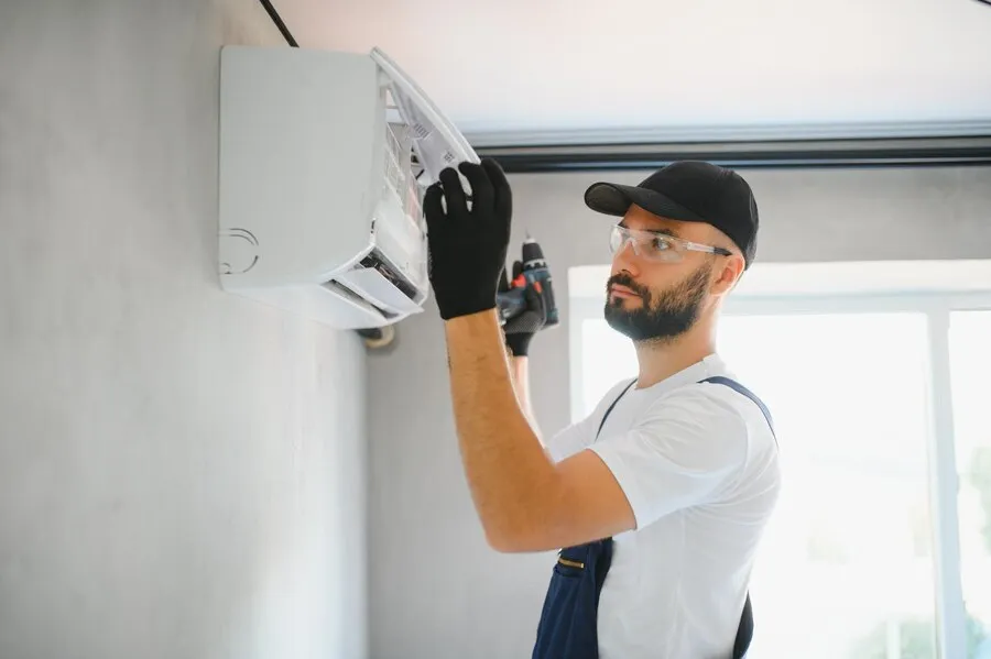 A person in white shirt is repairing a ductless AC unit