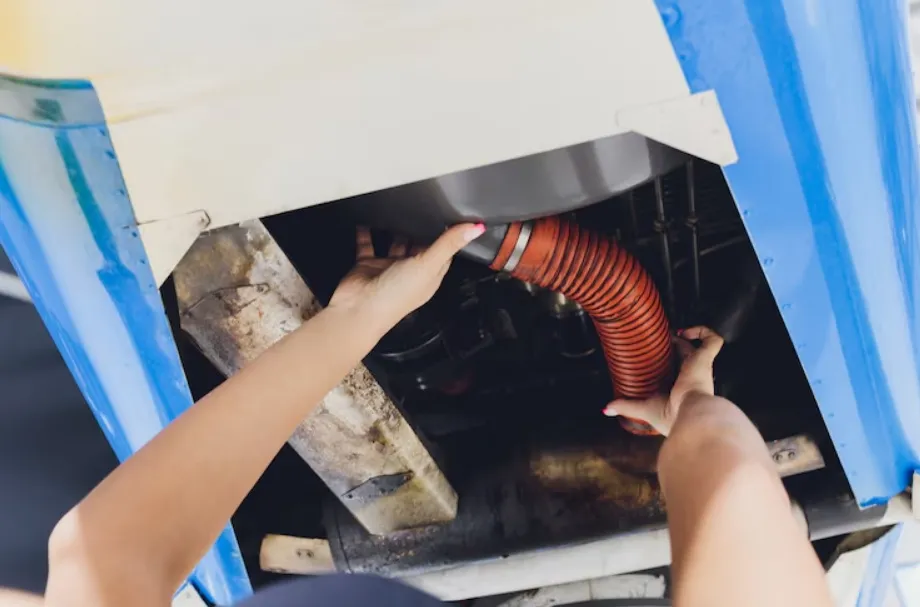 A close shot of person arranging a red pipe under an HVAC unit