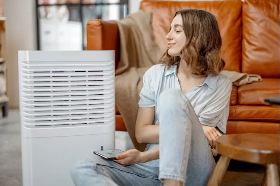 A girl standing next to a cooler fan