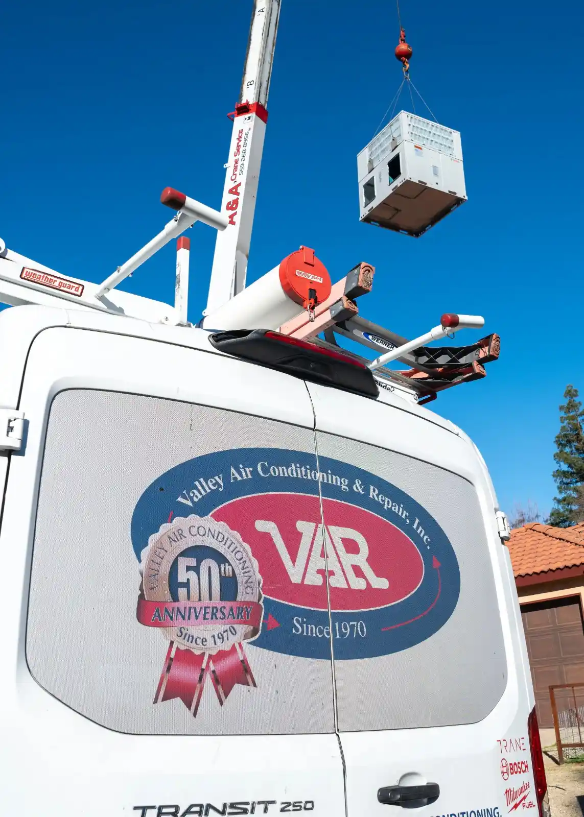 White Valley Air Conditioning & Repair van at intersection displaying company logo, services, contact number, and ladders