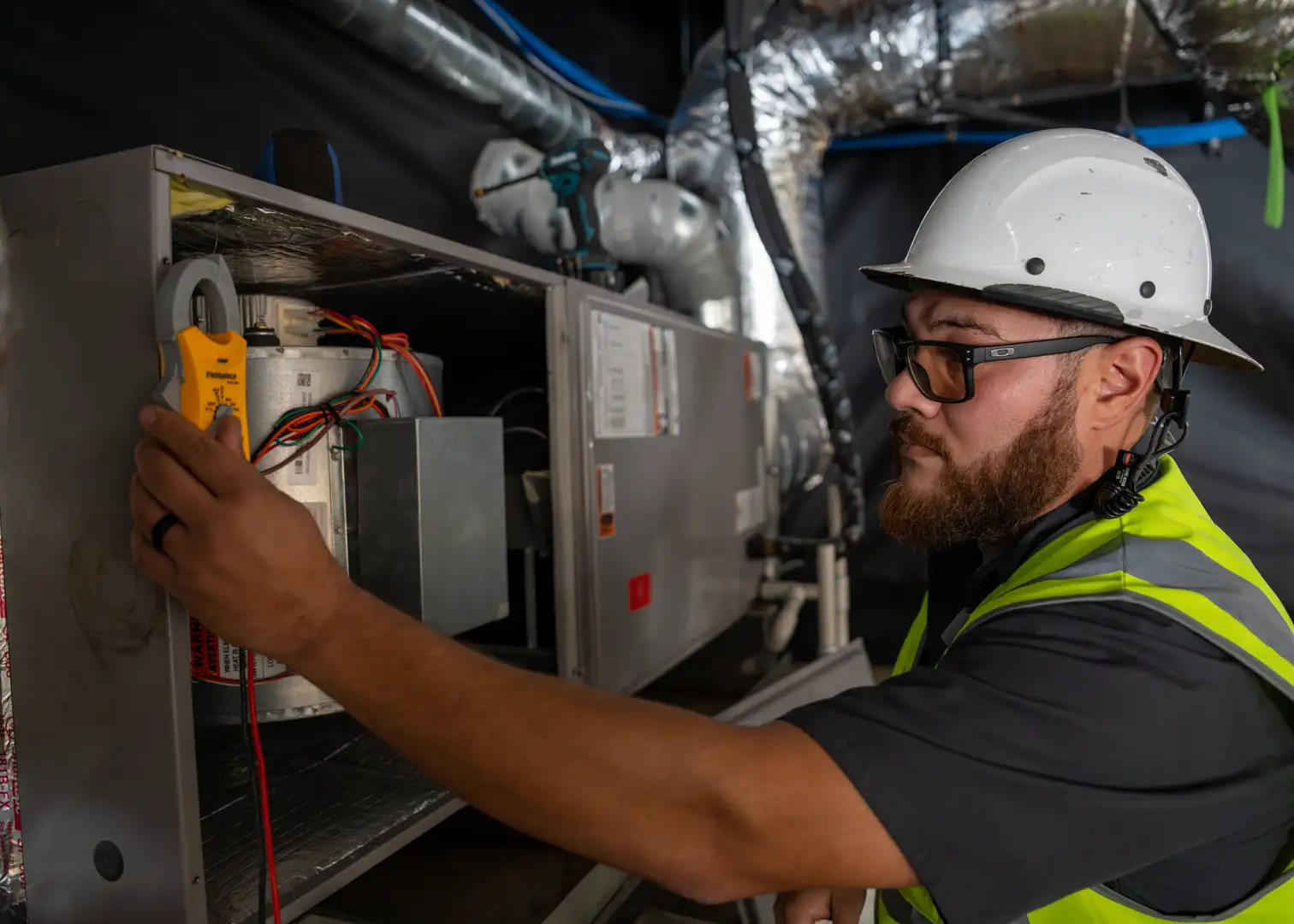 HVAC technician in Fresno using a digital multimeter to test the microfarad levels of an AC capacitor during a service call