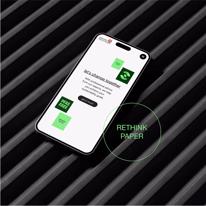 Smartphone zeigt Webseite mit Nachhaltigkeitsbotschaft, grüne Elemente und Aufschrift RETHINK PAPER auf dunklem geriffeltem Hintergrund.