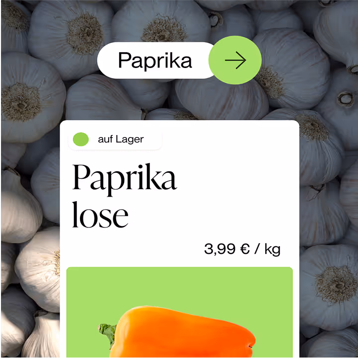 Produktanzeige einer losen Paprika mit Preis von 3,99 Euro pro Kilogramm vor Hintergrund mit Knoblauchknollen.
