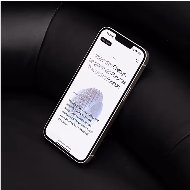 Smartphone liegt in schwarzem Lederstuhl, zeigt Webseite mit den Worten inspiriert von Wandel, Design mit Zweck und angetrieben von Leidenschaft.