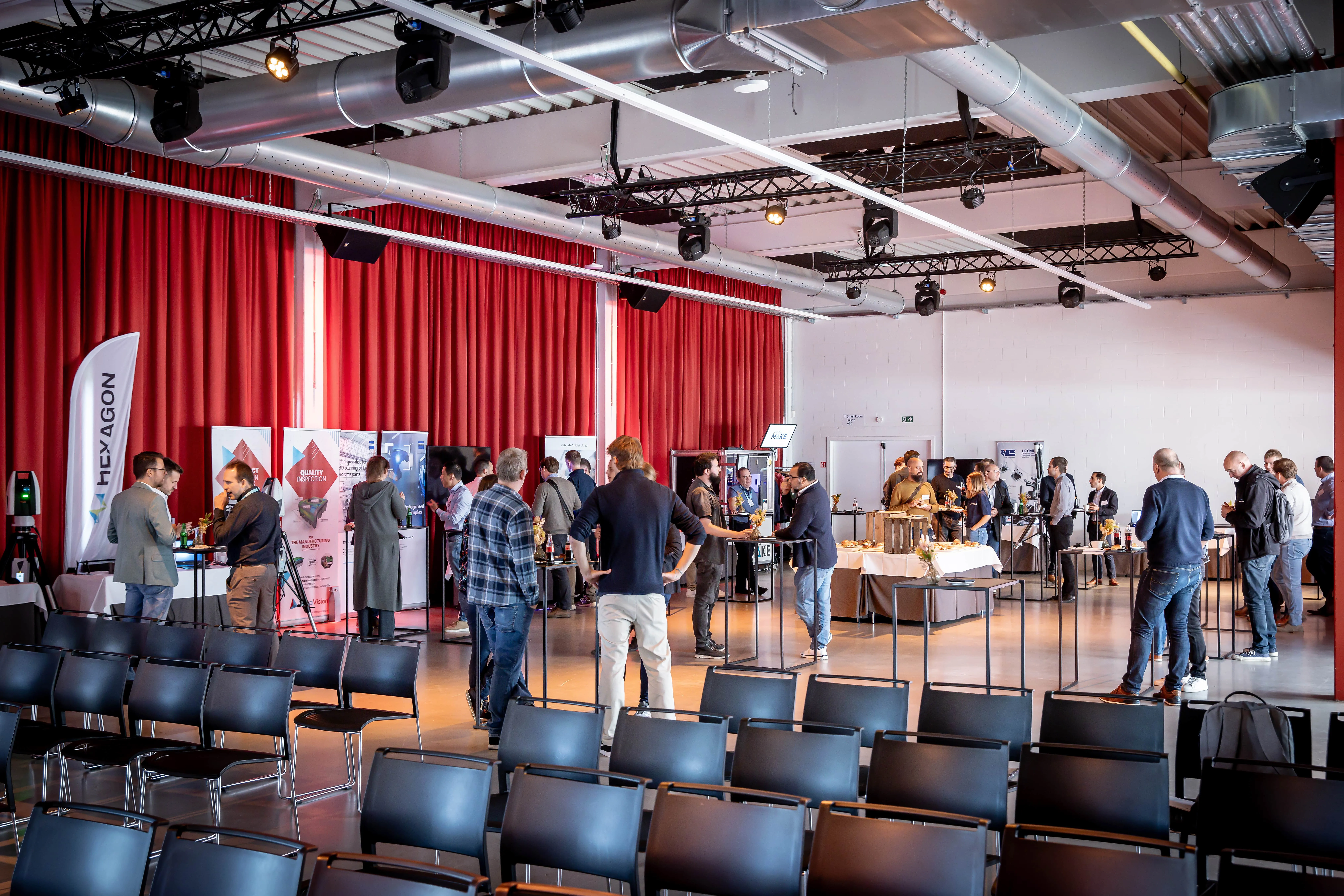 Bezoekers en partners bij stands tijdens een bedrijfsevenement in een eventlocatie.