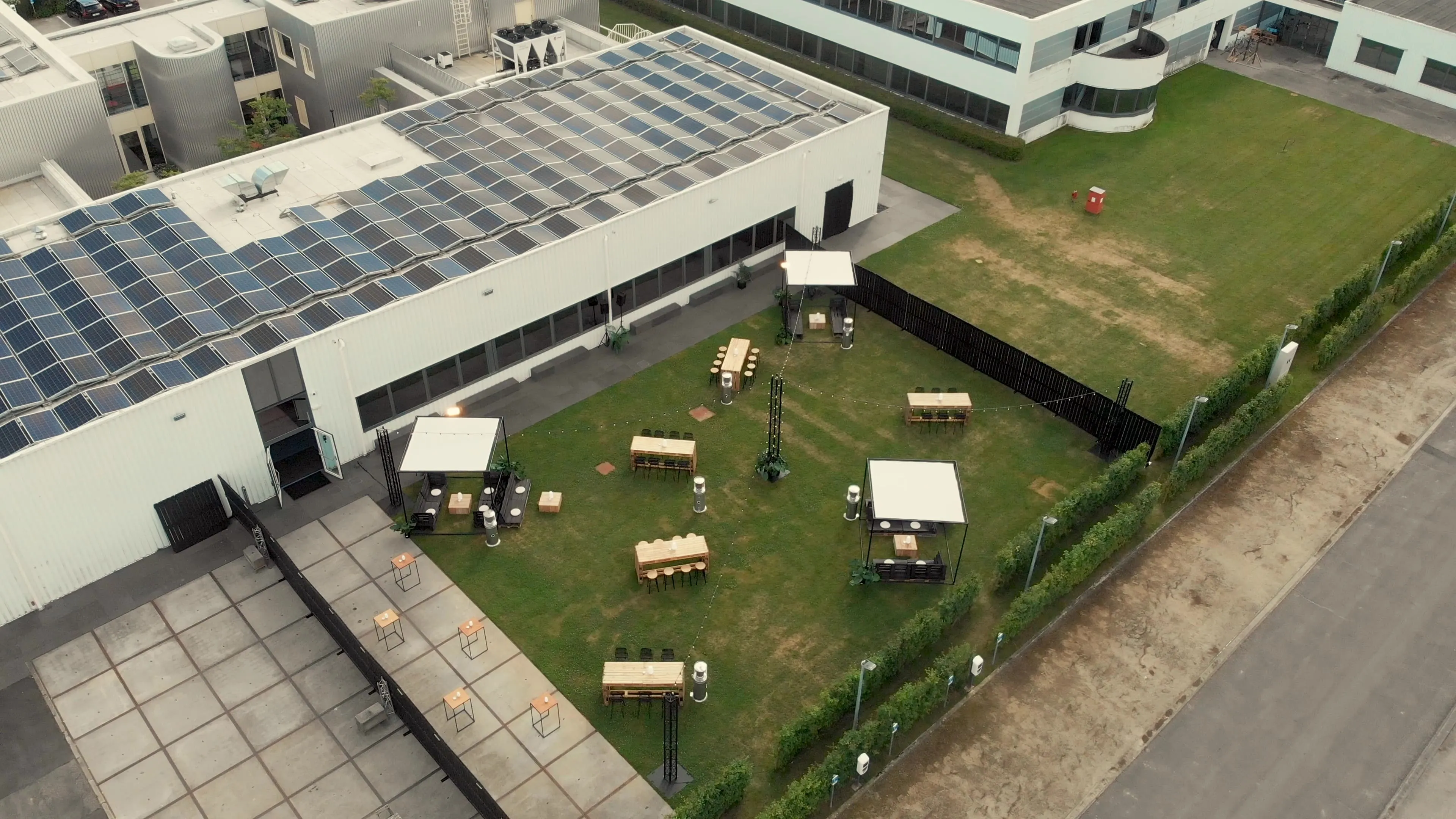 Bedrijfsevent met outdoor opstelling, tenten en tafels naast modern bedrijfsgebouw