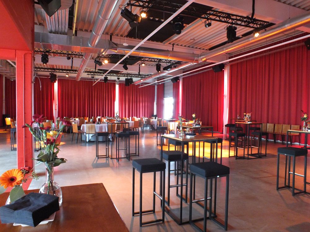 Eventruimte met statafels en sfeervolle verlichting voor bedrijfsevenement