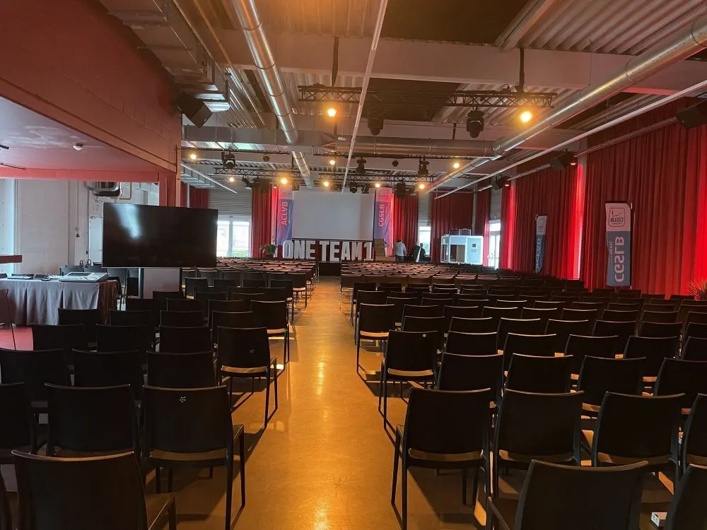 Overzicht van eventzaal met duidelijke opstelling van stoelen en zichtlijnen richting podium en signage