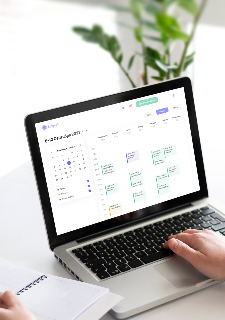 Person using a laptop displaying a weekly calendar schedule in Russian for September 6-12, 2021, with appointments in different colored blocks and a notebook beside the laptop.