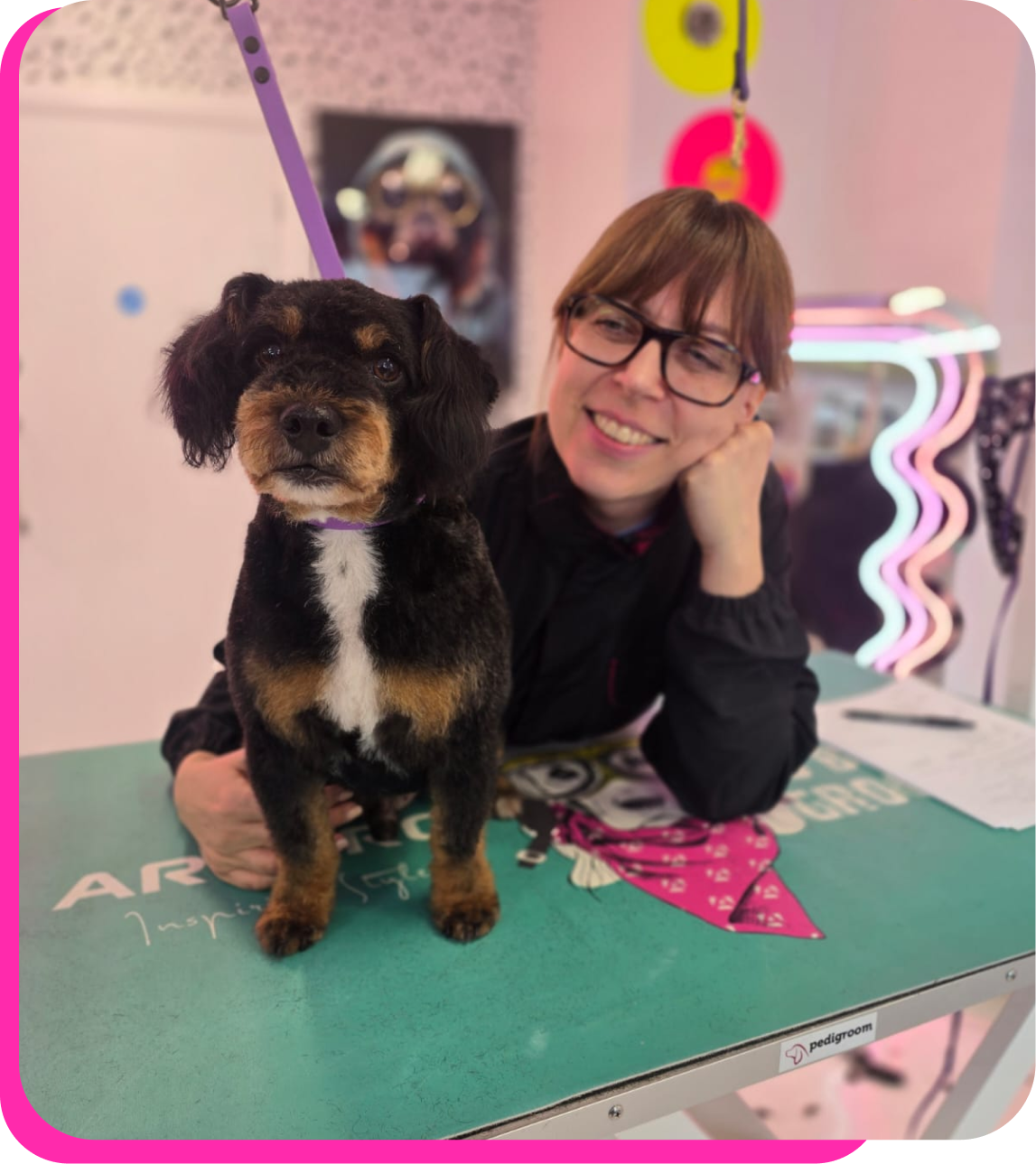 A student on a grooming taster day posing with a small black and tan dog on a grooming table at The Crazy Dog Ladies Grooming Academy salon in St Neots, Cambridgeshire.