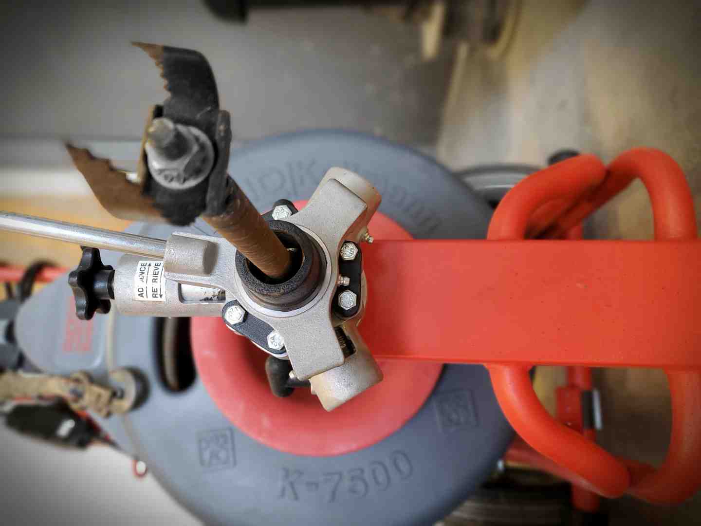 Professional technician using a mechanical drain snake auger to remove debris from a residential septic line