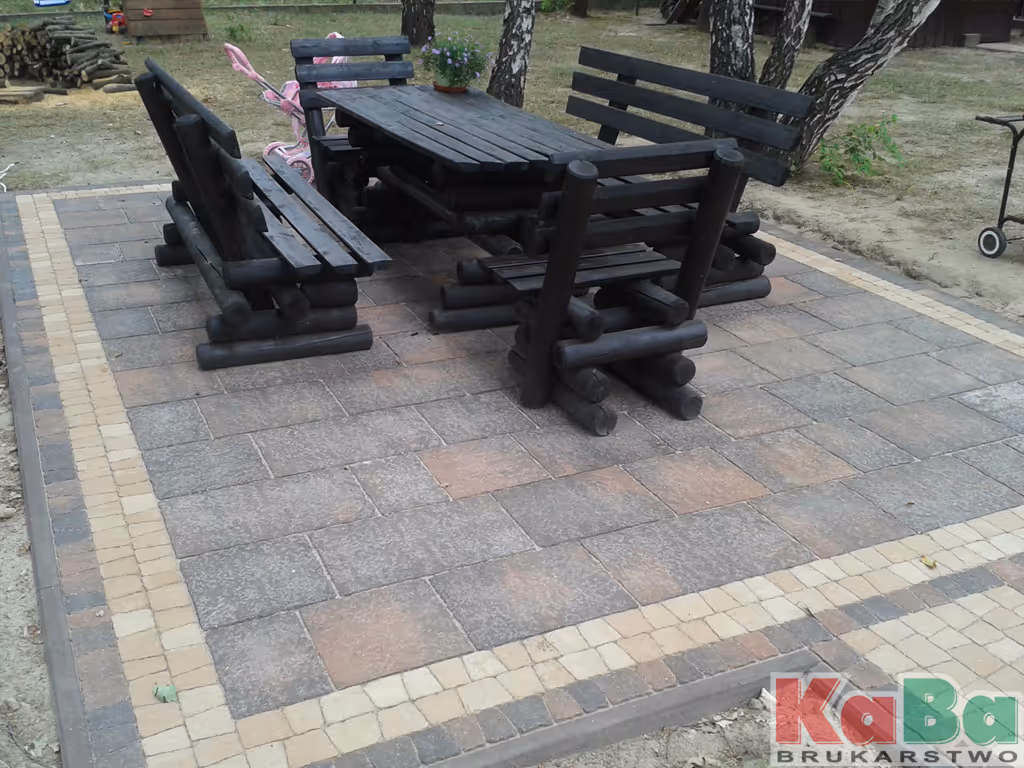 Zestaw drewnianych, czarnych mebli ogrodowych na podwórku z chodnikiem z kostki brukowej.