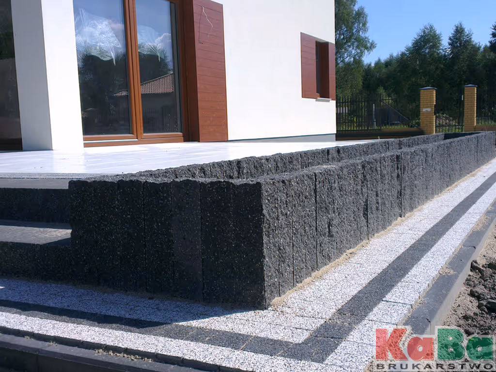 Murek konstrukcyjny z czarnych bloków betonowych przy tarasie nowoczesnego domu.