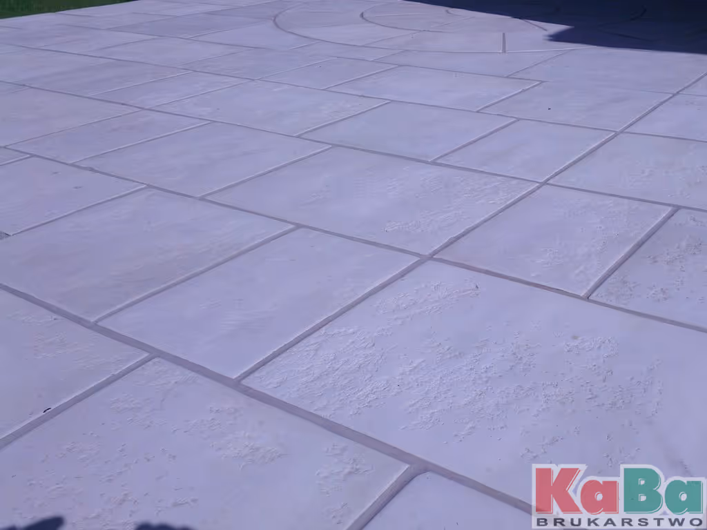 Plamy z dużych, jasnoszarych, prostokątnych płyt brukowych z fakturą.