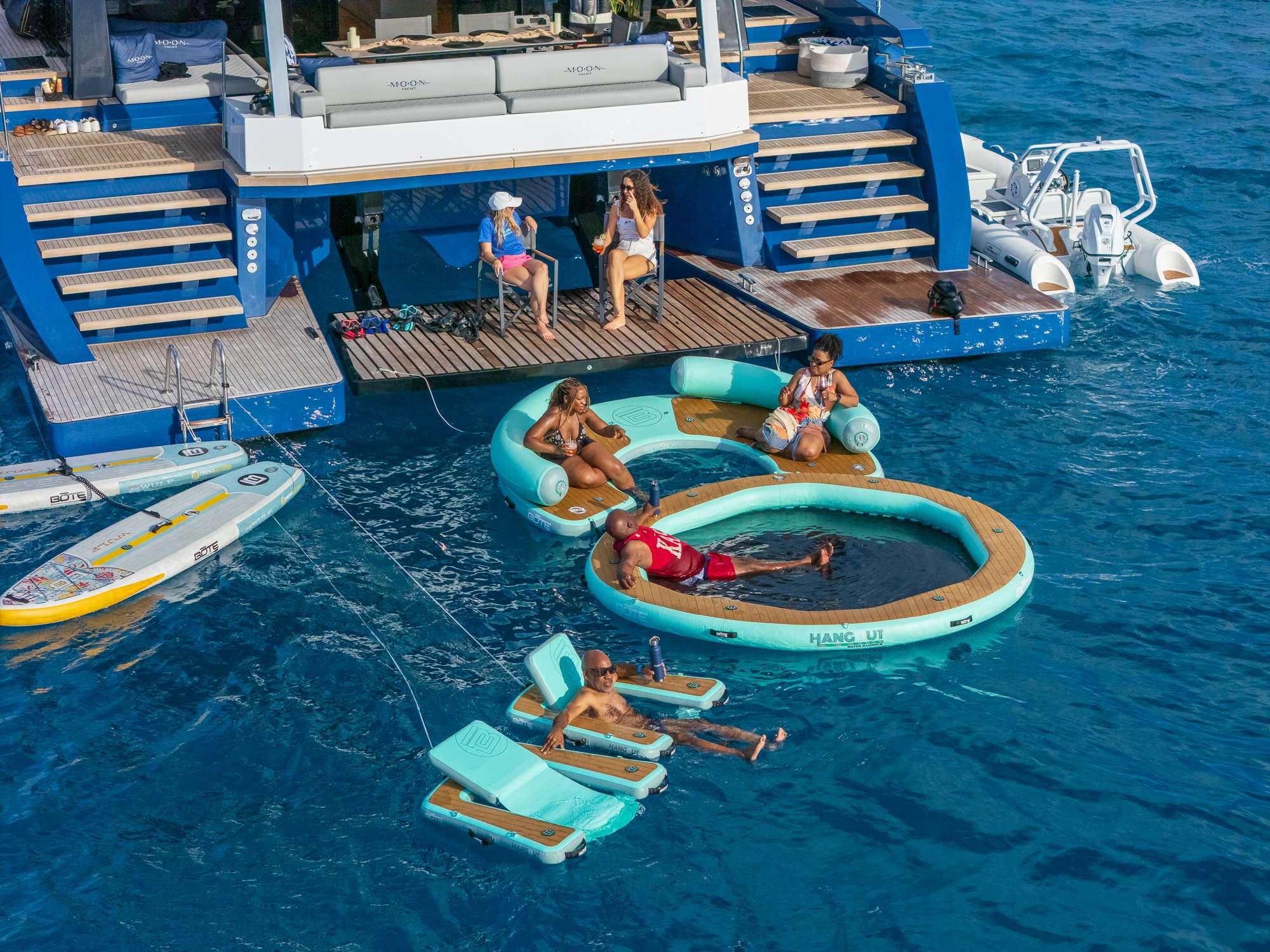 Guests relaxing on their yacht charter on catamaran swim platform and watertoys