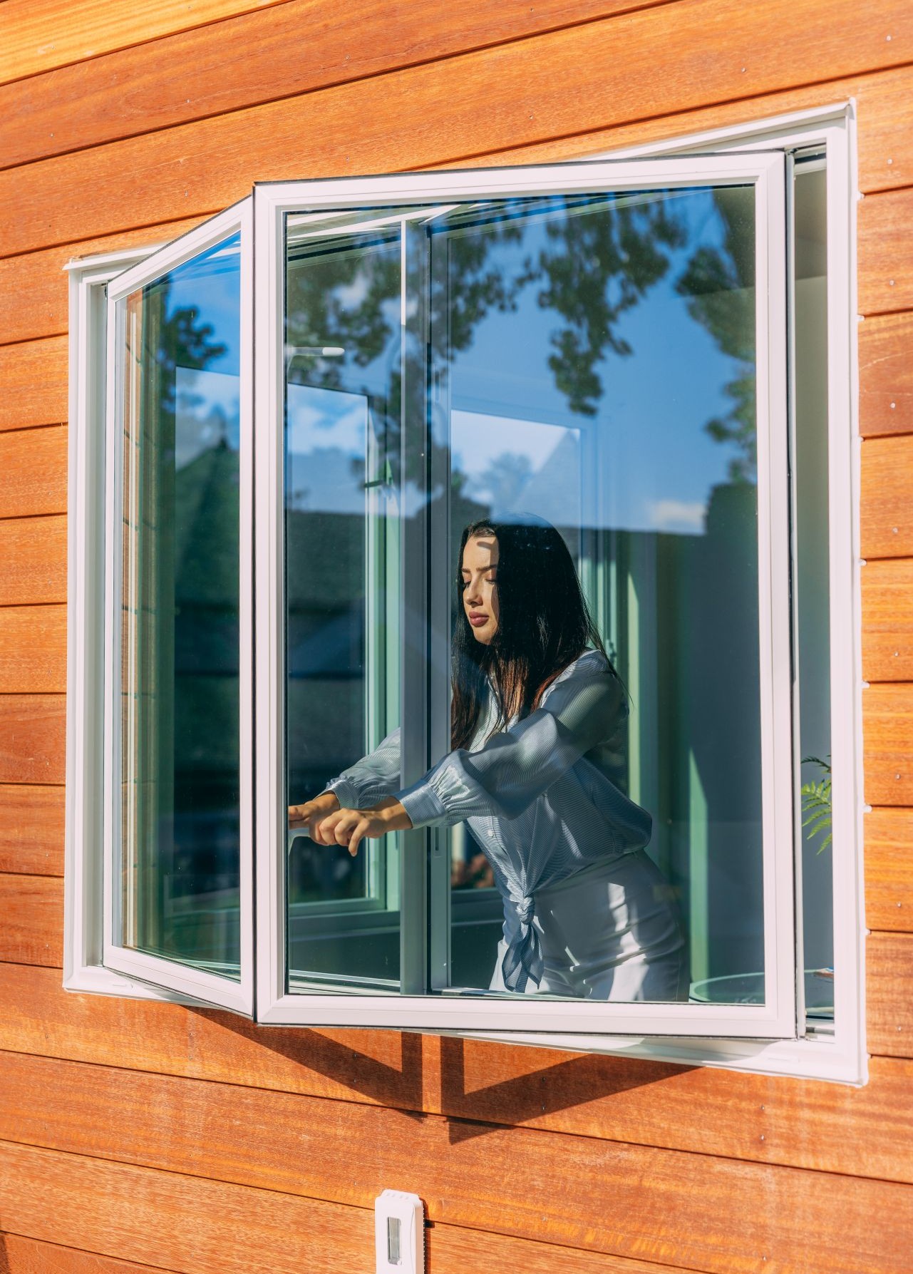 woman opening a crankless casement window