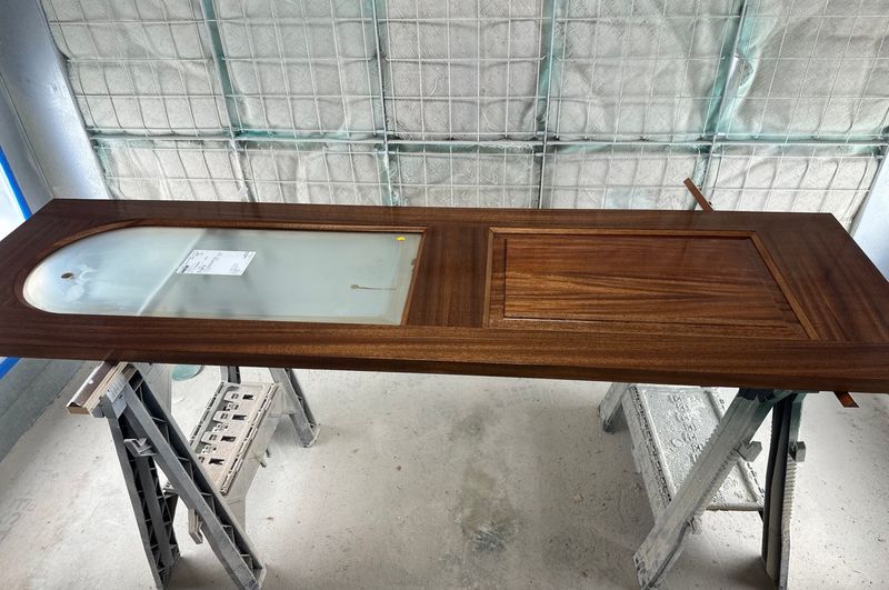 Custom solid wood door built in-house, resting on sawhorses in the workshop