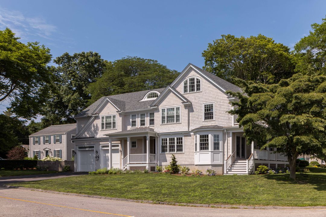 Finished shingle-style custom home exterior with a wraparound porch