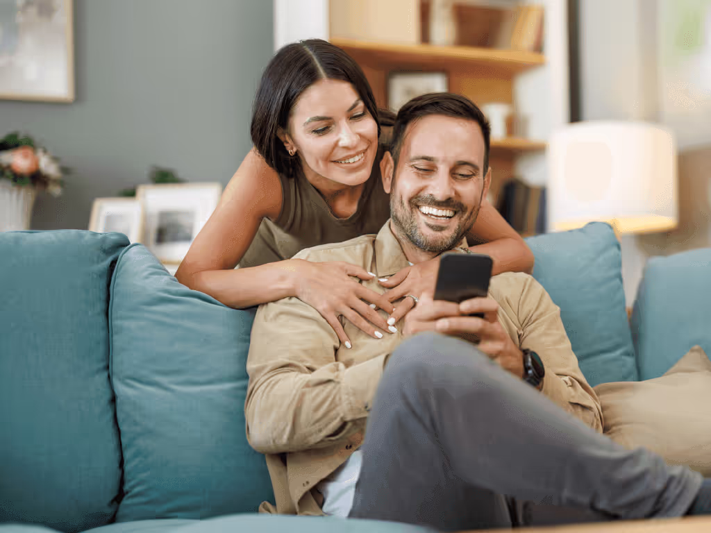 Woman and man embracing while looking a a mobile phone