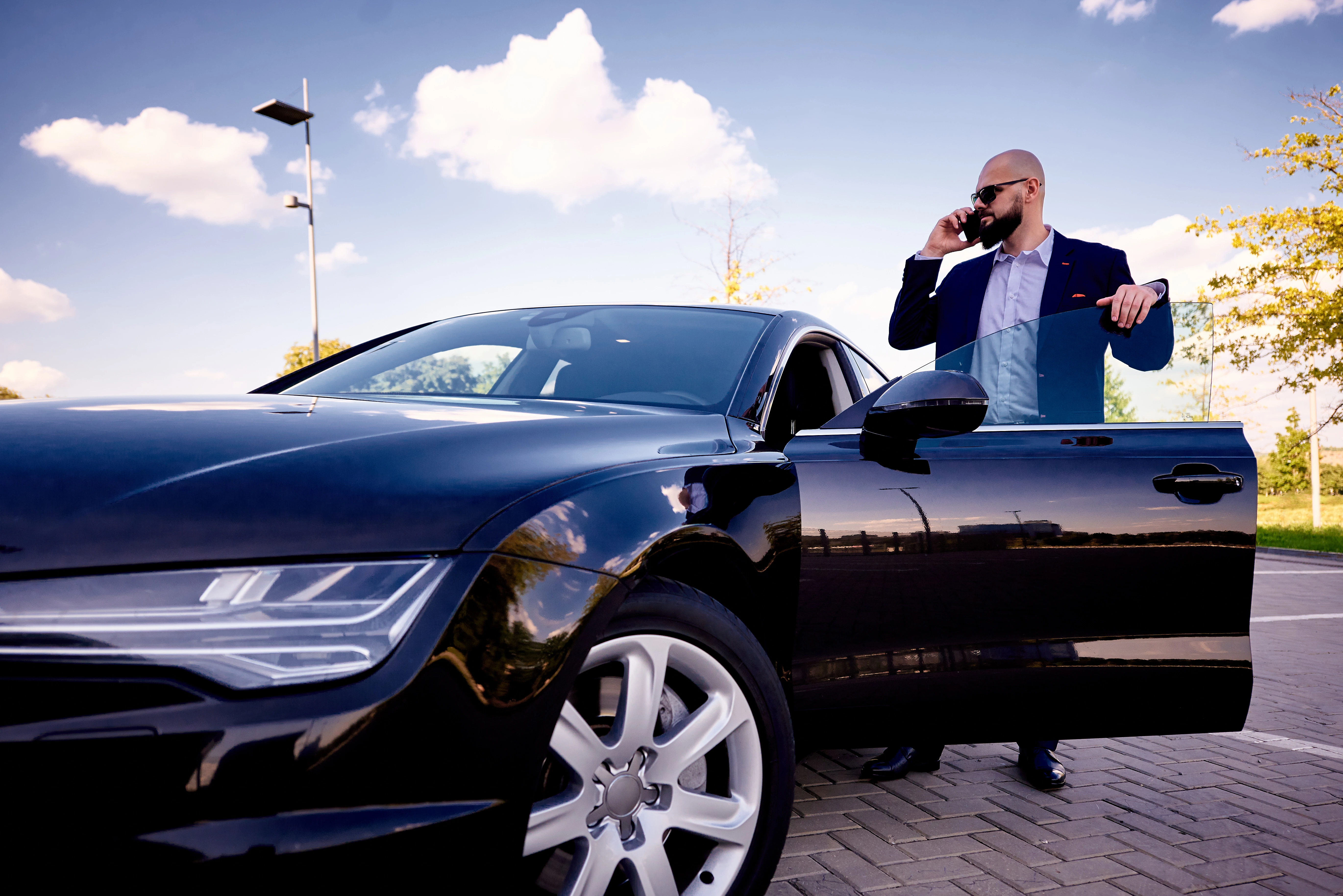 Un homme barbu portant une veste grise, regardant vers la droite dans un environnement boisé.