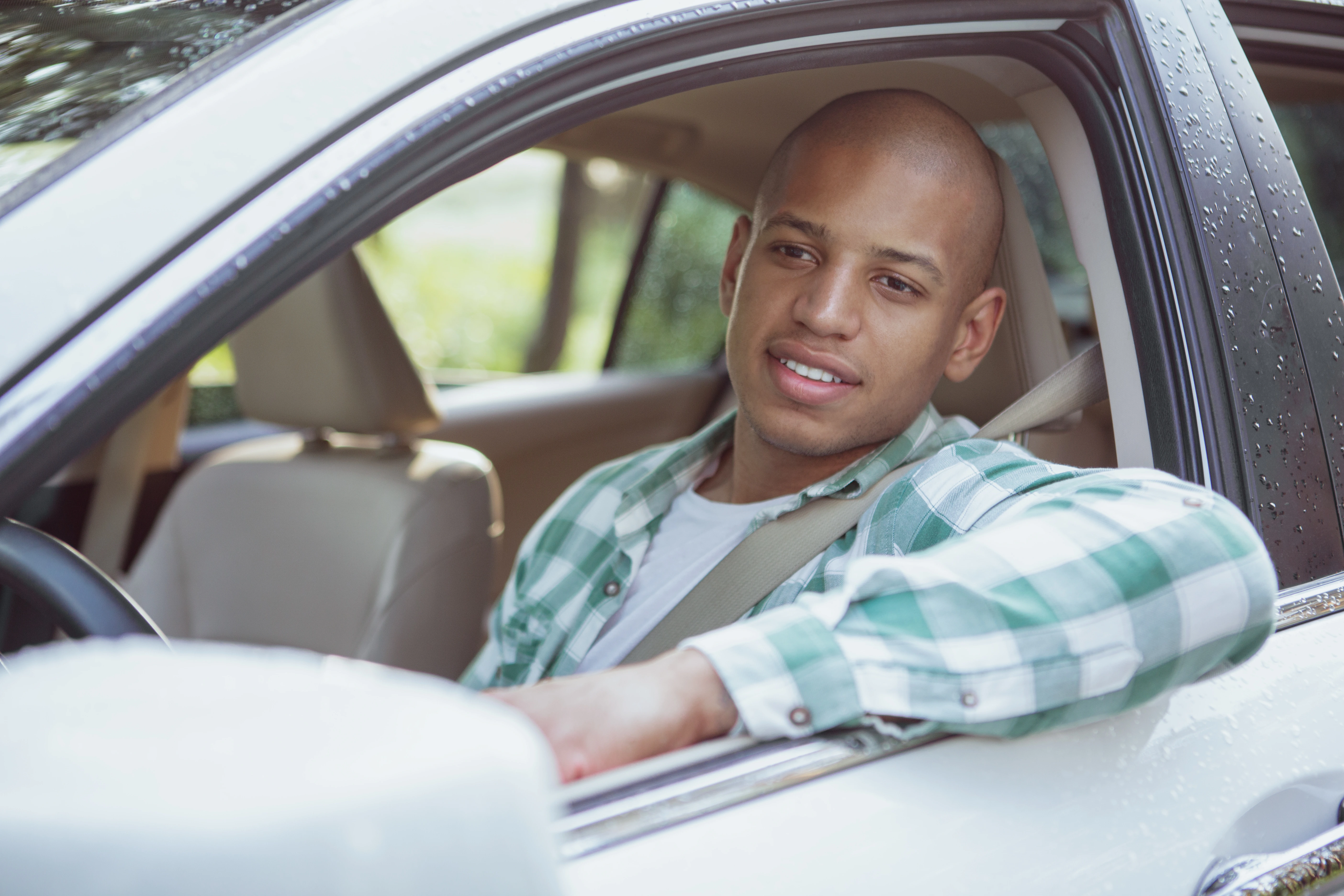 Jeune homme portant une chemise noire retirant ses lunettes de soleil avec un arrière-plan flou.