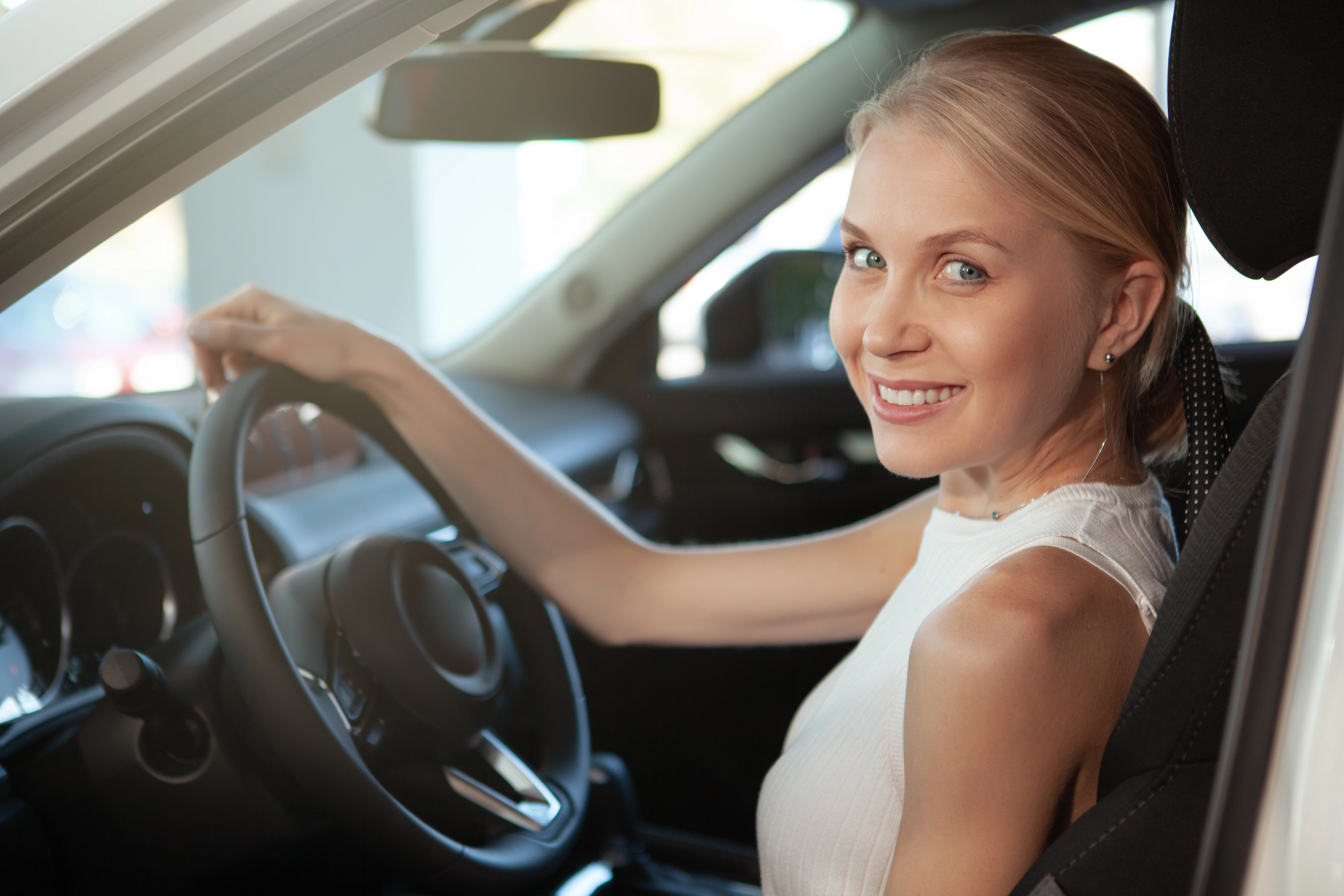 Portrait d'un homme aux cheveux bouclés, portant une chemise bleu foncé avec un collier simple, fond gris.