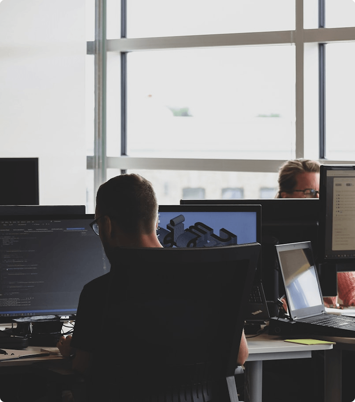 Tech professionals collaborating at their desks in a modern workspace, representing data synchronization and HR systems integration.