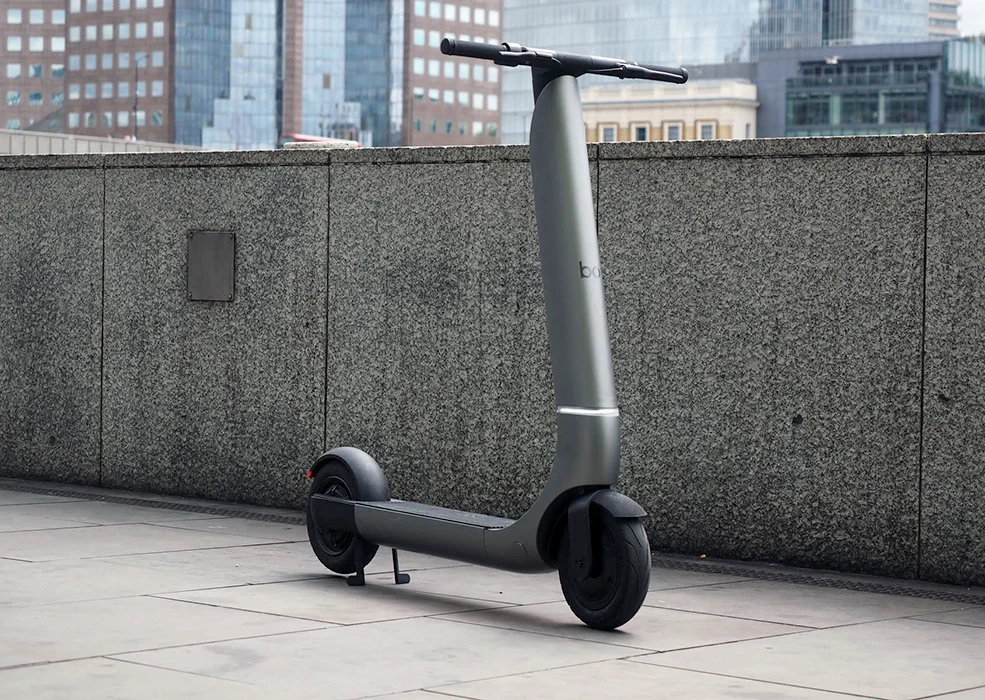 An electric scooter parked on a sidewalk in front of a wall