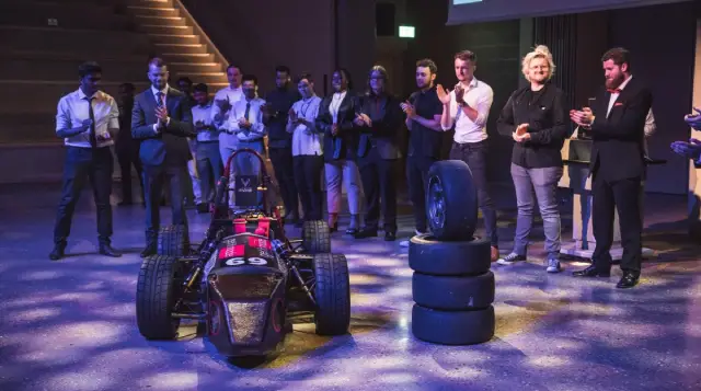 A group of people standing around a race car.