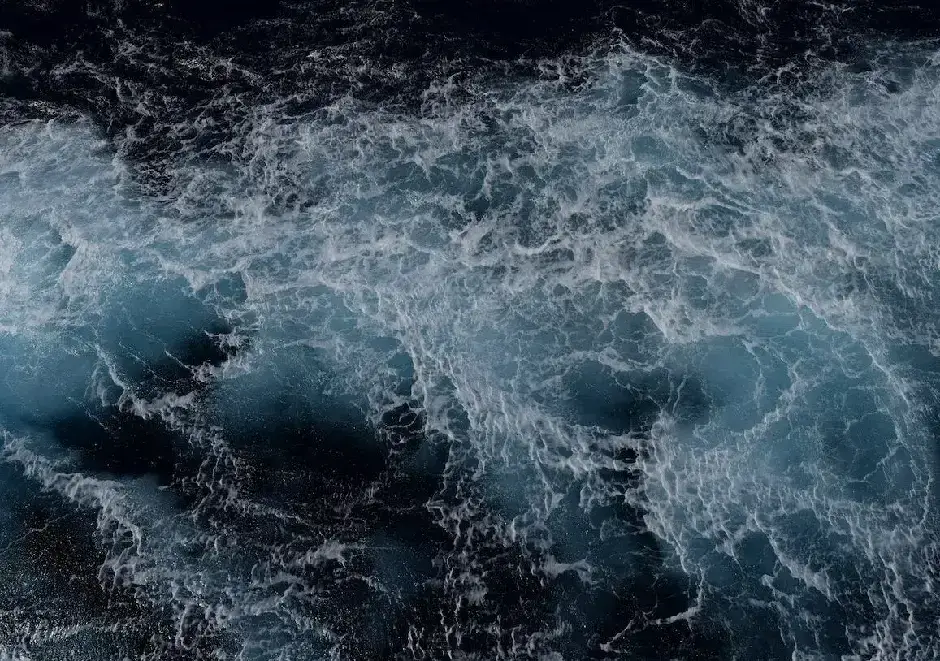 Turbulent ocean waves in dark blue and white, churning with intense energy
